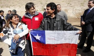 El minero Claudio Yañez (d), uno de "los 33 de Atacama", posa junto con su esposa y el ministro de Obras Públicas, Laurence Golborne, antes del inicio de un homenaje a los trabajadores rescatados en Copiapó (Chile). Los 33 trabajadores recibieron un emotivo homenaje de familiares, amigos y autoridades al cumplirse un año de la operación que los rescató sanos y salvos, tras permanecer 70 días atrapados a 700 metros de profundidad. Foto: Felipe Trueba / Efe