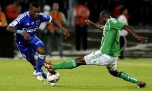 El jugador de Atlético Nacional Juan David Valencia disputa el balón con Junior Fernandes, de la Universidad de Chile). Foto: Luis Eduardo Noriega / Efe