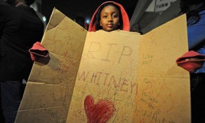 Una niña, seguidora de la cantante y actriz estadounidense Whitney Houston, que murió el sábado a los 48 años de edad en el Hotel Beverly Hilton, por causas que se investigan, muestra una pancarta donde se lee 'Descansa en Paz, Whitney', en Los Ángeles, California (EE UU). Foto: Michael Nelson / Efe