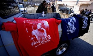 Seguidores de la cantante estadounidense Whitney Houston venden camisetas con su imagen cerca de la iglesia baptista Nueva Esperanza, donde se celebró su funeral, en Newark, Nueva Jersey, EE.UU, este sábado. La cantante, que tenía 48 años, fue encontrada el pasado 11 de febrero "inconsciente" en la bañera de la habitación del hotel en el que se alojaba por un miembro de su equipo y fue declarada muerta por el personal de los servicios de emergencia que intentaron reanimarla sin éxito, según la versión policial. Foto: Peter Foley / Efe
