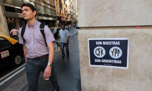 BUENOS AIRES (ARGENTINA).- Un hombre camina junto a un afiche que hace referencia a la nacionalización de la petrolera YPF este miércoles 18 de abril de 2012, en Buenos Aires (Argentina). La intervención estatal en la petrolera argentina YPF ha puesto en marcha una auditoría de la empresa y ha decidido aumentar su producción, entre otras medidas dentro del proceso de su expropiación a la española Repsol, informaron fuentes oficiales.