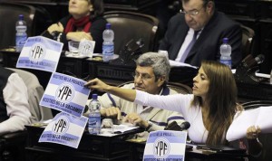 BUENOS AIRES (ARGENTINA) - Los diputados del Frente Amplio Progresista, Victor De Gennaro (i) y Victoria Donda (d), colocan carteles con el logo de YPF en las bancas de los diputados este miércoles, durante la sesión de la Cámara de Diputados en Buenos Aires. El pleno de la Cámara inició una sesión de dos días para debatir el proyecto de ley que establece la expropiación del 51 por ciento de las acciones de la empresa española Repsol en la petroleraYPF.
