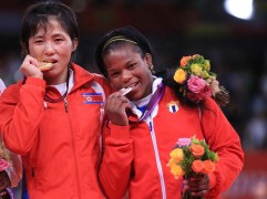 LONDRES (GRAN BRETAÑA).- La norcoreana An Kum Ae (oro) y la cubana Yanet BermoyAcosta (plata) muerden sus medallas tras la final en la categoria de -52 kg. en los Juegos Olímpicos de Londres, este 29 de julio 2012.